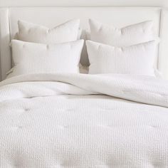 a bed with white linens and pillows on it