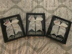 two framed pictures with bows on them sitting on a bed