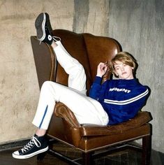 a boy sitting in a chair with his feet up