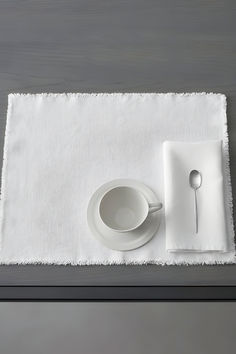 a white place setting with silverware and napkins