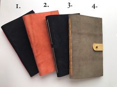 four notebooks lined up on top of each other in different colors and sizes,