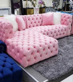 a pink and blue couch sitting on top of a gray rug next to a mirror