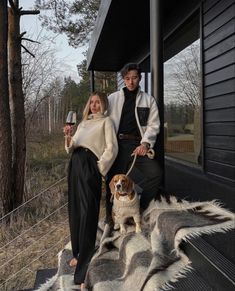 a man and woman holding wine glasses while standing next to a dog