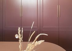 a vase filled with dry grass sitting on top of a table next to cupboards