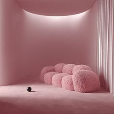 a room with pink walls and flooring that has round pillows on the floor in front of it