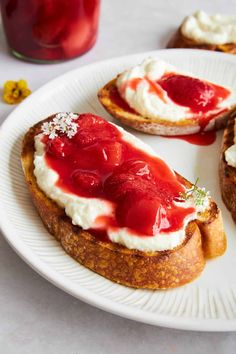 two pieces of bread with cream cheese and strawberry jam on them, sitting on a plate