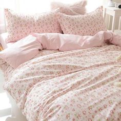 a bed with pink sheets and pillows on it