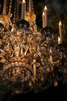 a crystal chandelier with candles lit in the dark