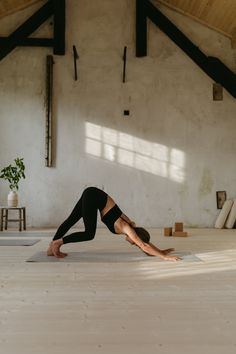 a woman is doing yoga in a room with white walls and wooden beams on the ceiling