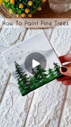 someone is painting pine trees on a piece of paper and then using scissors to cut them