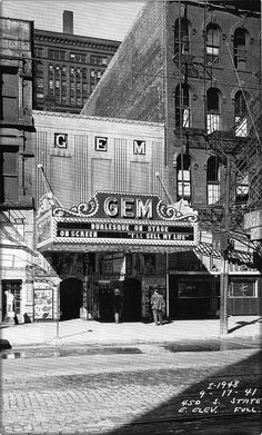 an old black and white photo of a theater in the middle of a city street