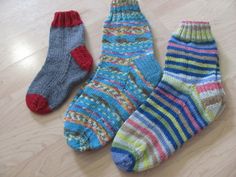 three pairs of multicolored socks laying on top of a wooden floor next to each other