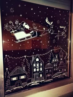 the window is decorated with santa's sleigh and reindeers flying through the night sky