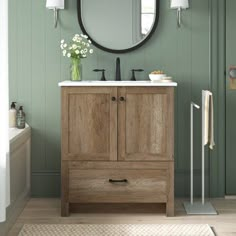 a bathroom with green walls and a round mirror on the wall above the sink, along with a rug