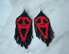 two pairs of beaded earrings with red and black designs on them sitting on a marble surface