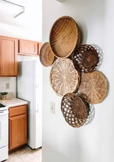 several baskets hanging on the wall above an oven in a kitchen with wood cabinets and white appliances