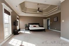 a bedroom with a bed, ceiling fan and two windows in the middle of it