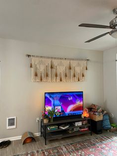 a flat screen tv sitting on top of a wooden stand in a living room next to a window