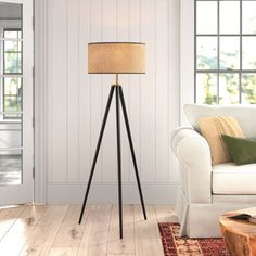 a living room with a white couch and a lamp on top of a wooden floor