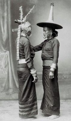 two women dressed in costumes and hats standing next to each other with their hands together