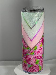 a pink and green vase sitting on top of a white table next to a wall