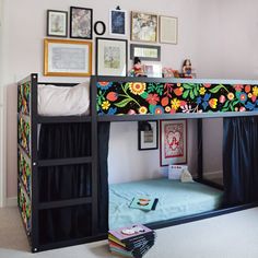 a bunk bed with a colorful floral design on the top and bottom, next to a stack of books