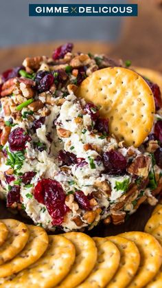 a cheese ball with crackers and cranberries on top is sitting next to some crackers