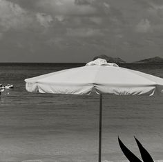 an umbrella on the beach with people in the water