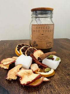 apples, oranges and cinnamon peels are on a table next to a jar of spiced hot toddy