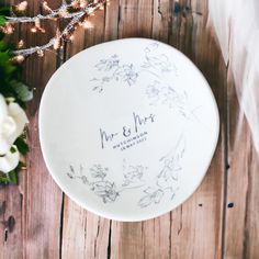 a wedding cake plate with the name mr and mrs written on it next to flowers