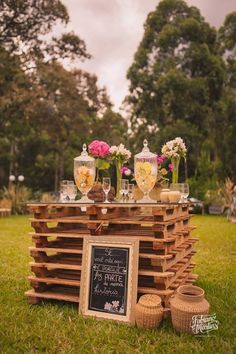 a wooden table topped with glasses and vases on top of green grass covered ground