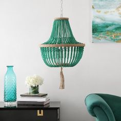 a green chair sitting next to a table with a vase on top of it and a chandelier hanging from the ceiling