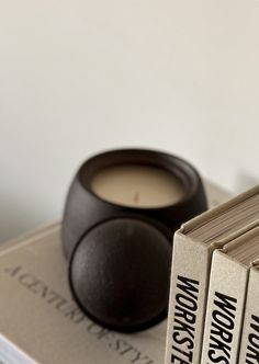 three books sitting on top of each other with a candle in front of one book