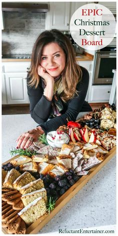 a woman sitting in front of a table full of desserts and crackers with the words epic christmas dessert board