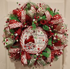 a christmas wreath on the front door decorated with candy canes and holly berries,