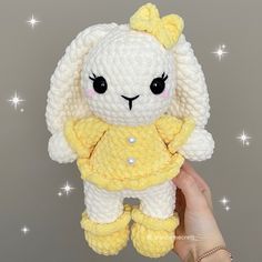 a hand holding a small stuffed animal in yellow and white colors with stars on the background