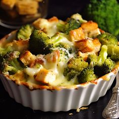 a casserole dish with broccoli, cheese and bread on the side