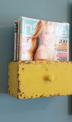 a magazine rack with magazines on it in front of a blue wall and a yellow door