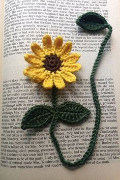 a crocheted sunflower sitting on top of an open book with green string