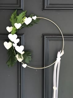 a wreath with white hearts hanging on the front door, decorated with greenery and ribbon