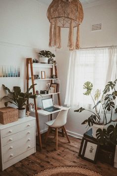 a room with a desk, shelves and plants on the wall next to a window