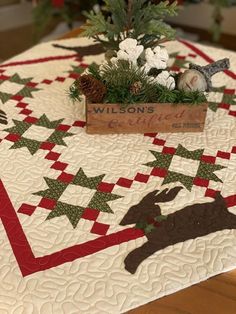 a quilted table top with a wooden box on it and christmas decorations in the center