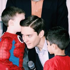 a man and two young boys sitting next to each other in front of a microphone