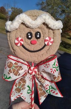 a hand holding up a brown and white gingerbread man ornament with candy canes