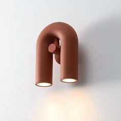 a wall mounted light on the side of a white wall next to a brown lamp