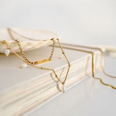 CA$37.00 · With a taste for adventure and an opinion on every subject - Bridget, eternal romantic - is turning the page on a whole new life. With gleaming pearls on her neck, she will finally find the love of her life. The Bridget is a gold pearl choker necklace made of a stainless steel satellite chain. Five delicate freshwater pearls hang proudly around its length. Gold Pearl Choker, Square Bar, Bracelets Design, Gold Bar Necklace, Gold Pearl Necklace