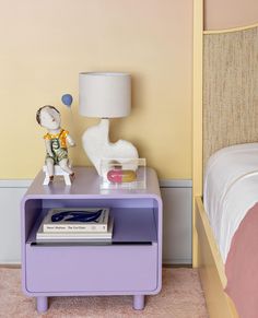 a nightstand with a book on it next to a bed