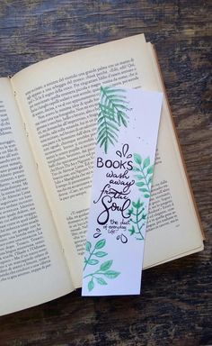 an open book with some green leaves on it and the words books are written in black ink