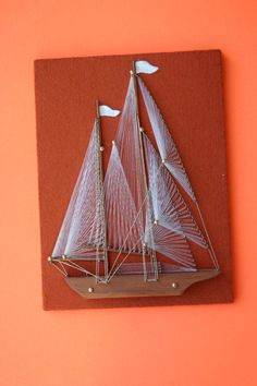 a white sailboat on an orange background with red paper and gold trimmings