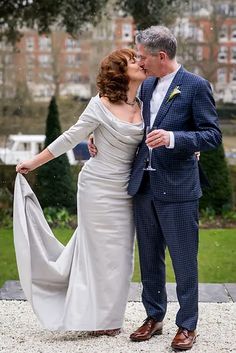 a bride and groom kissing in the rain